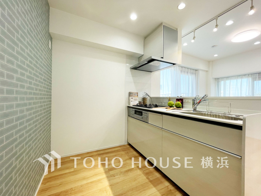 開放的な対面キッチン。おしゃれなタイル壁と木目フローリングが調和した快適な空間です。