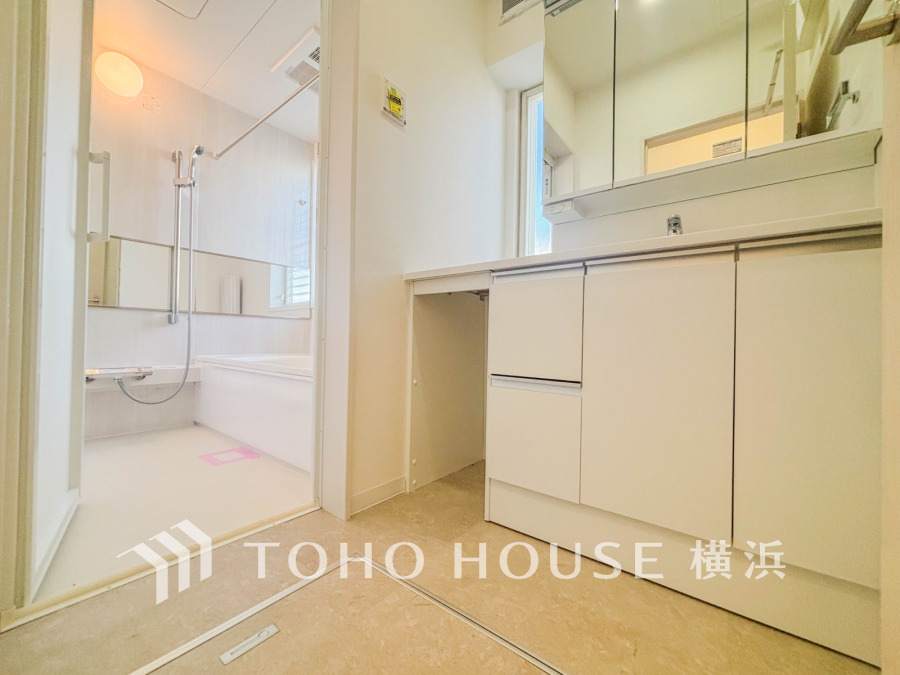 清潔感あふれる白基調の洗面所と浴室。明るい窓から自然光が差し込み、快適な空間を演出します。