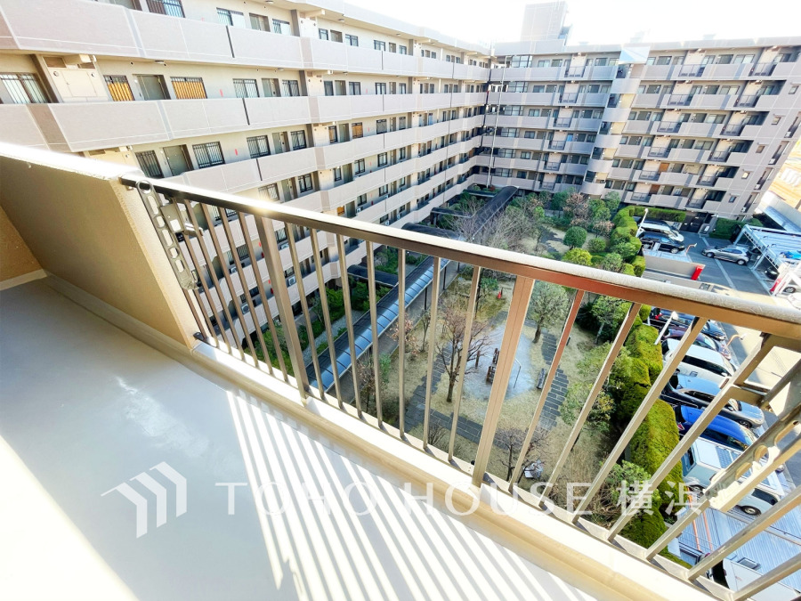 陽光が差し込むバルコニーから、緑豊かな中庭と駐車場を見渡せる開放的な眺望が魅力です。