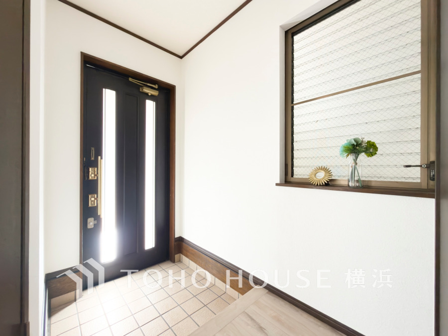 明るく清潔感のある玄関。大きな窓から自然光が入り、快適な第一印象を演出します。