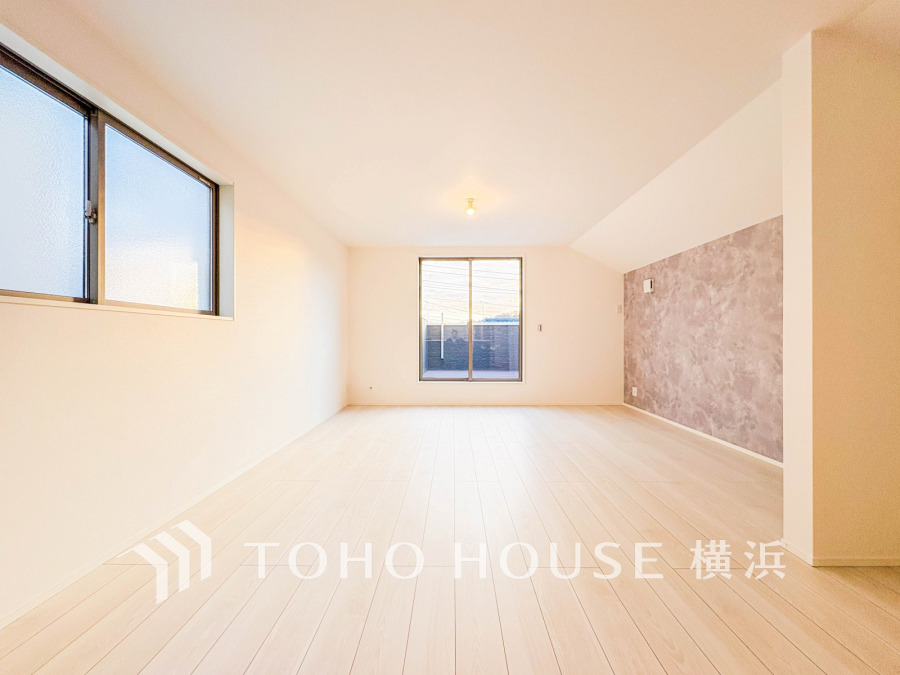 明るい自然光が差し込む広々としたリビング。アクセントクロスが空間に上質な雰囲気を演出します。