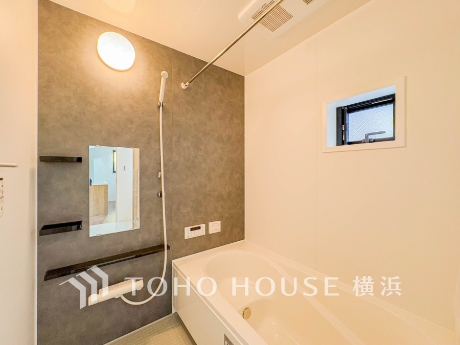 落ち着いたグレーの壁がアクセントの清潔感あるバスルーム。小窓で自然換気も可能です。