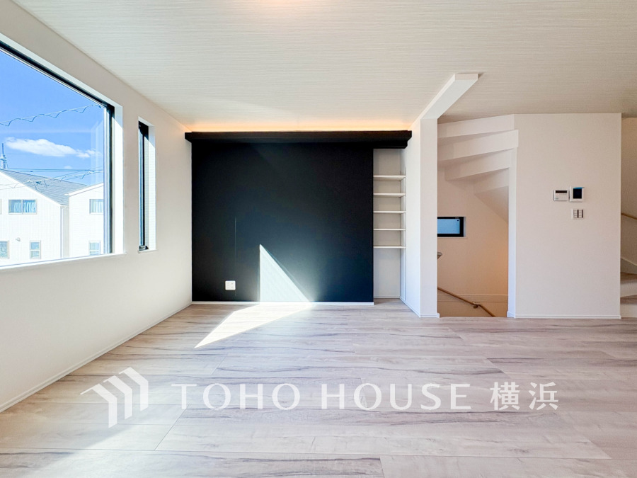 大きな窓から光が差し込む、シンプルでモダンなリビング空間。黒のアクセント壁が空間を引き締めます。