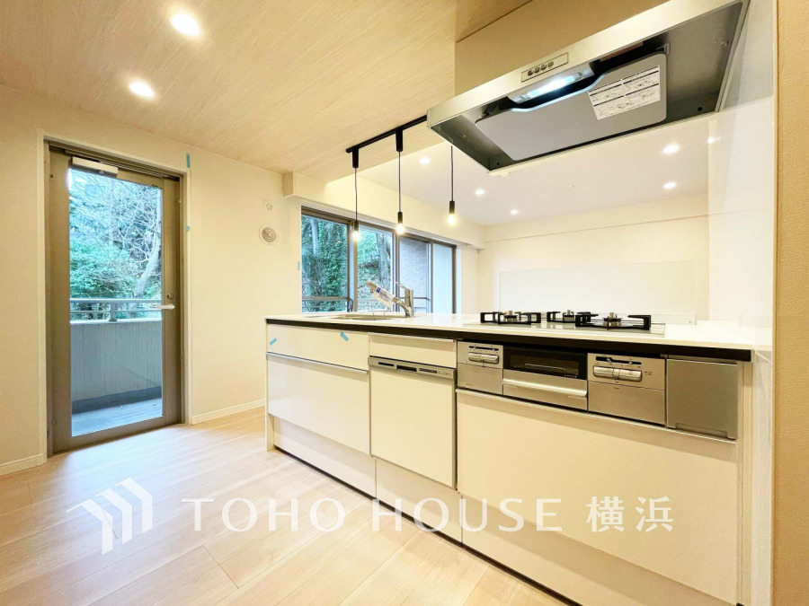 明るい自然光が差し込む、機能的でスタイリッシュなシステムキッチン。バルコニーへの出入りもスムーズです。