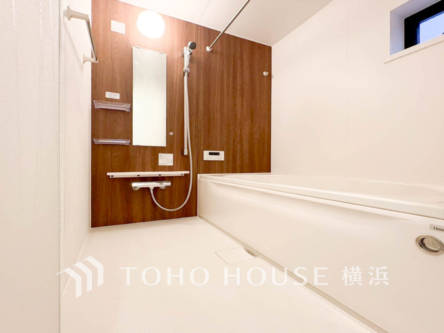 木目調パネルが温かみを演出する、清潔感あふれるゆったりとしたバスルームです。