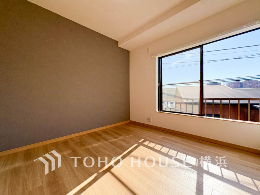 大きな窓から自然光がたっぷり入る、落ち着いたアクセントクロスの洋室です。