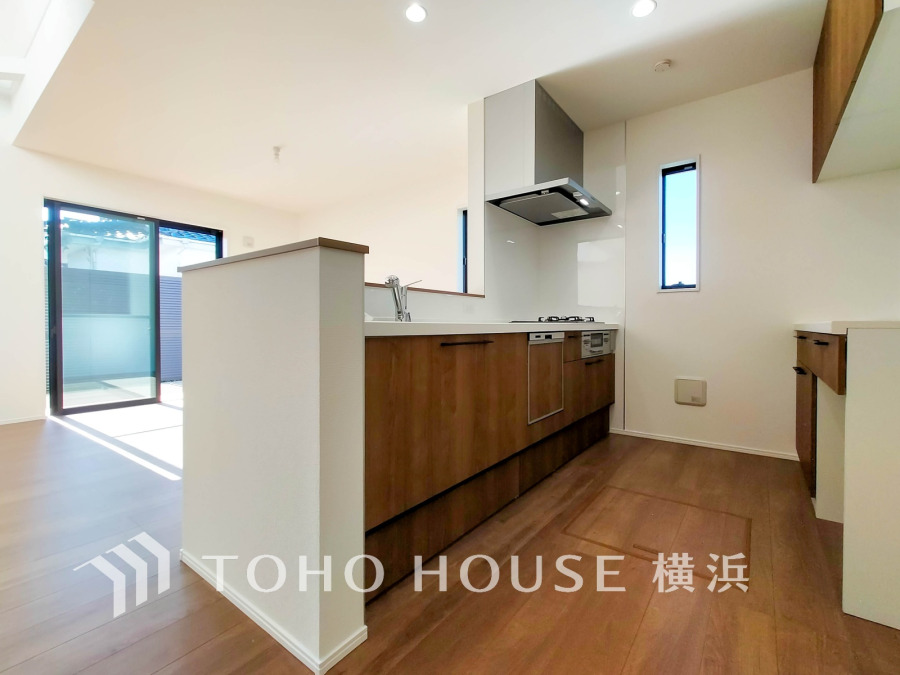 明るい自然光が差し込む、木目調の収納が豊富な使い勝手の良い対面キッチンです。