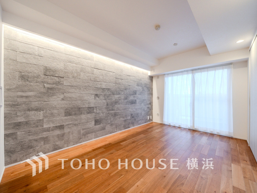 天然木の床と間接照明が調和する、落ち着いた雰囲気のリビングルームです。大きな窓で明るさも十分。