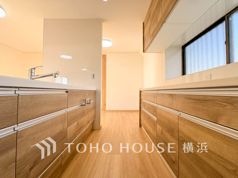 温かみのある木目調の収納が両側に並ぶ、使い勝手の良い明るいキッチン空間です。