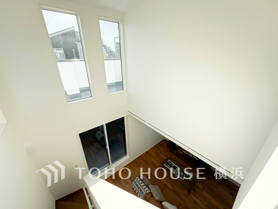 吹き抜けから自然光が降り注ぐ明るいリビング。開放感あふれる空間設計で心地よい住まいを実現。