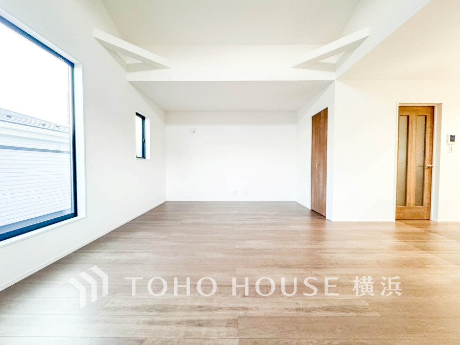 大きな窓から自然光が差し込む、開放感あふれる明るいリビング空間。木目調の床が温かみを演出します。