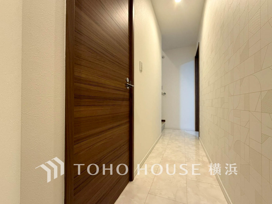 清潔感あふれる白を基調とした廊下。木目調の扉が温かみを添え、落ち着いた雰囲気を演出します。