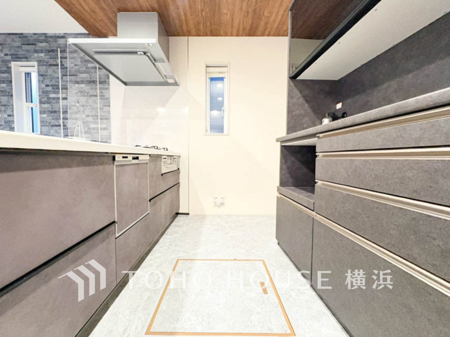 スタイリッシュなグレーの収納と木目天井が調和する、機能的で明るいキッチン空間です。