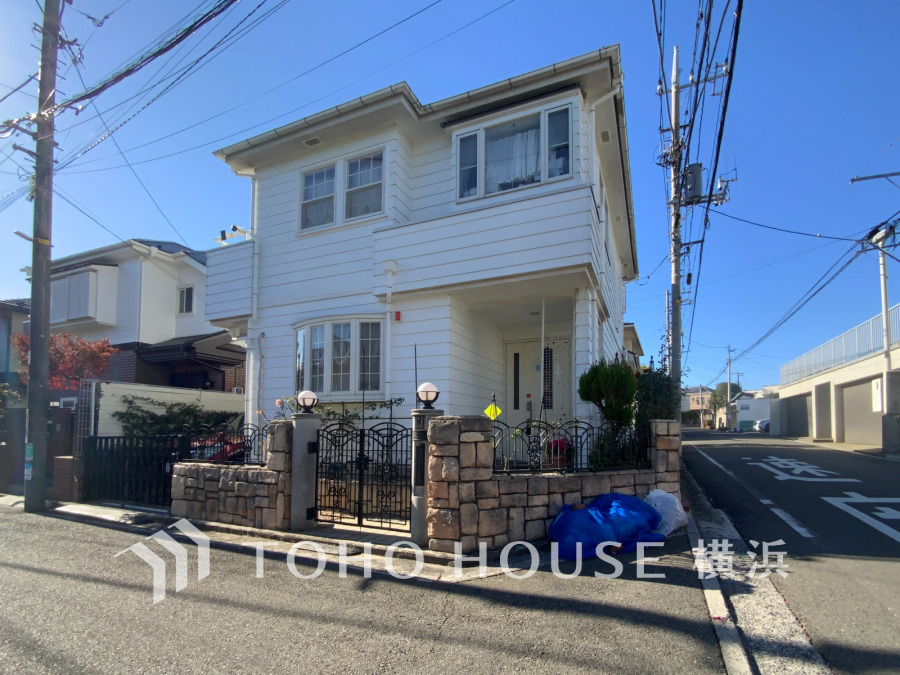 角地に建つ、白い外壁が爽やかな2階建ての戸建住宅。日当たり良好で開放感のある住まいです。