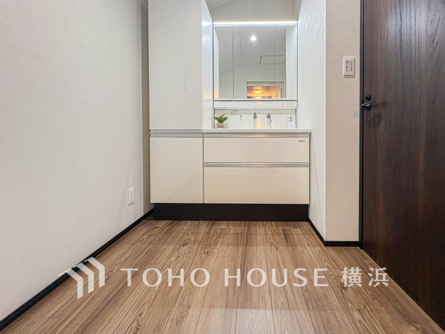 木目床が温かみを添える洗面スペース。大容量収納付きで使い勝手良く、清潔感あふれるデザインが魅力です。