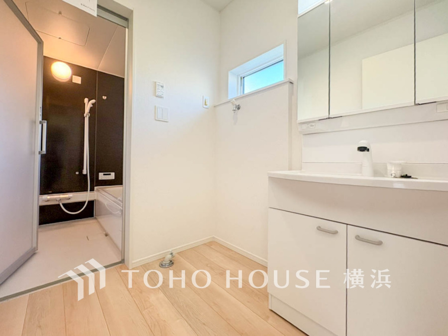 清潔感あふれる洗面所と、ブラックアクセントの浴室が調和した機能的で明るい水回り空間です。