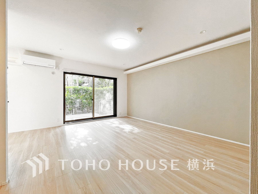 自然光が差し込む、明るく広々としたリビングルーム。ナチュラルな床材と落ち着いたアクセントウォールが魅力です。