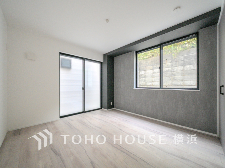 落ち着いたグレーのアクセント壁と大きな窓で明るく開放的な空間。