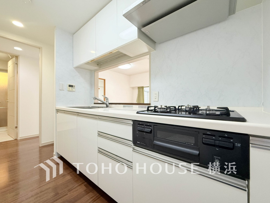 清潔感あふれるホワイトカラーのシステムキッチン。リビングの様子を見ながら調理ができる便利な対面式です。