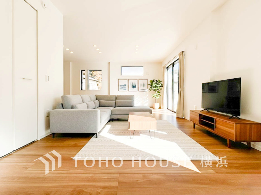 陽光が差し込む広々としたリビング。シンプルで落ち着いた色合いが心地よい寛ぎの空間を演出します。