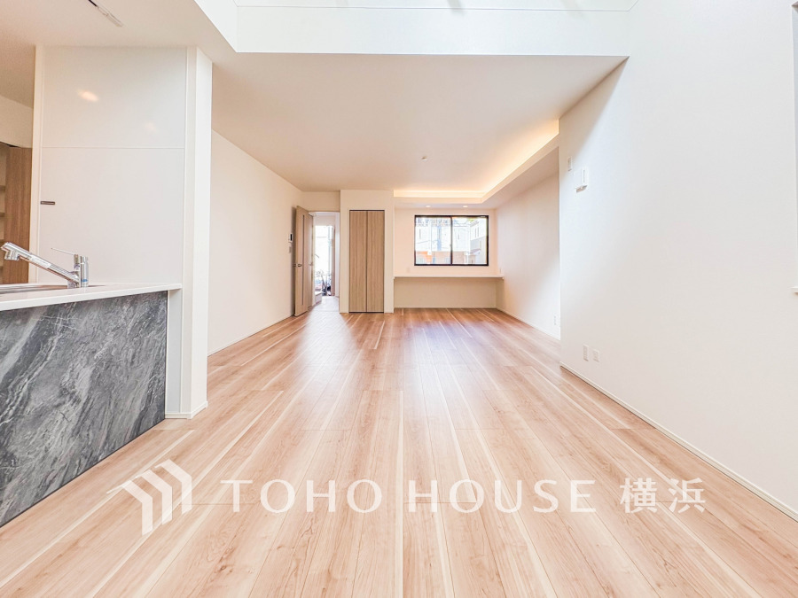 明るい自然光が差し込む広々としたリビング。木目調のフローリングとシンプルな白壁で落ち着いた空間を演出。