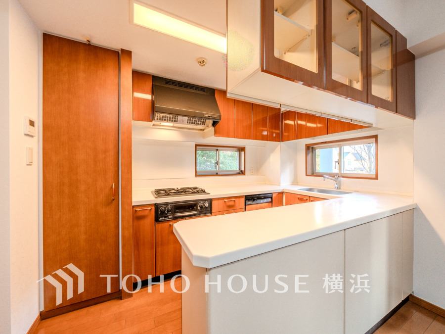 木目調の収納と白いカウンターが調和した、明るく機能的なキッチンです。窓から自然光もたっぷり。