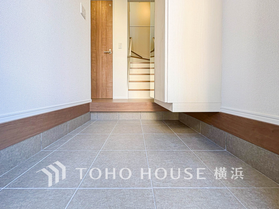 清潔感あふれる広々とした玄関。収納棚と姿見鏡で使い勝手とおしゃれを両立した空間設計です。