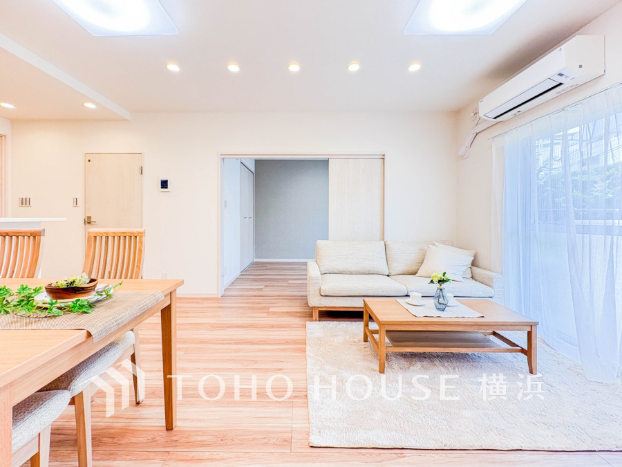 自然光がたっぷり入る明るいリビング。ナチュラルな木目とシンプルな家具で落ち着いた空間を演出しています。