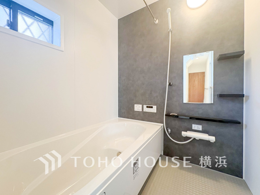 落ち着いたグレーの壁が映える、清潔感あふれるバスルーム。ゆったりくつろげる浴槽付きです。