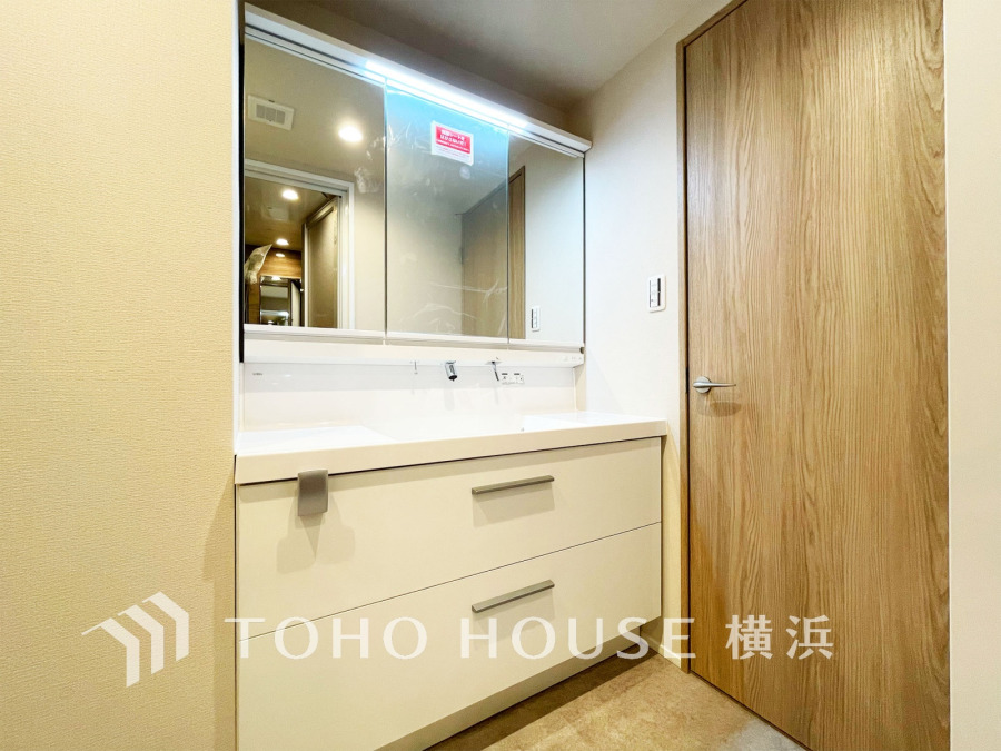 清潔感あふれる洗面台は大容量収納付きで、毎日の身支度が快適に行えます。木目調の扉が温かみを演出。