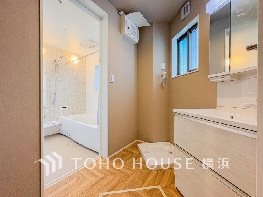 ナチュラルな色合いと木目調フロアが温かみを演出する洗面室。浴室と一体で使いやすさも良好です。