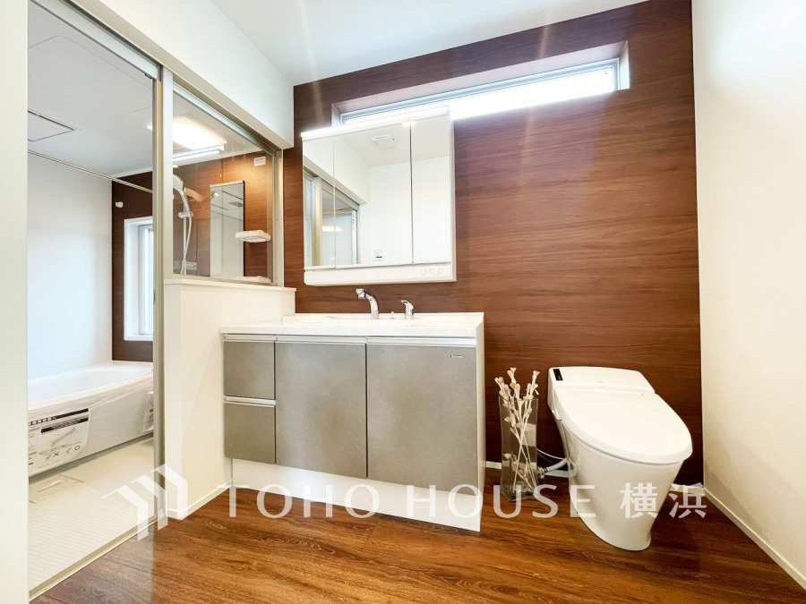 木目調の落ち着いた壁面と機能的な洗面台が調和した、清潔感あふれるモダンな洗面・トイレ空間です。