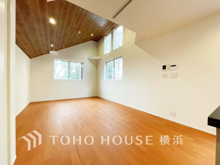 ウッディな勾配天井が印象的な開放感あるリビング。大きな窓から自然光がたっぷり入り、明るく快適な居住空間です。