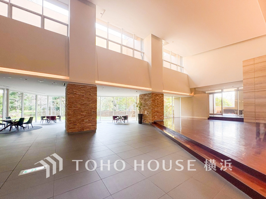 開放感あふれる高い天井と大きな窓で自然光がたっぷり入り、落ち着いた共用ラウンジ空間を演出しています。