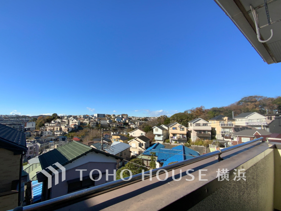 晴天の空が広がるバルコニーからの眺望。緑豊かな丘陵地に広がる閑静な住宅街を一望できます。