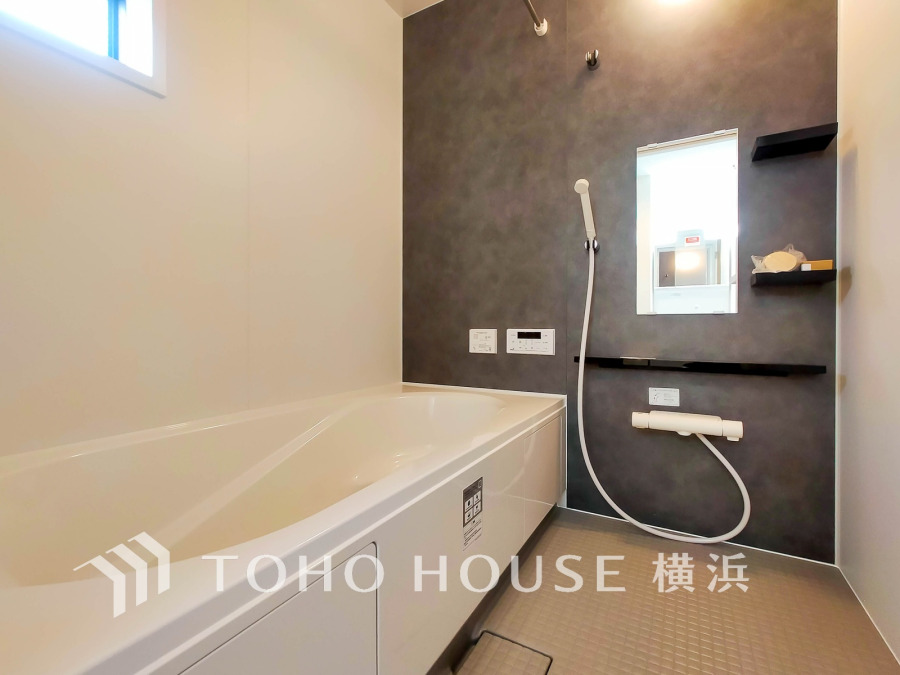 シックなアクセントウォールが印象的な清潔感あふれるバスルーム。ゆったりくつろげる浴槽を備えています。