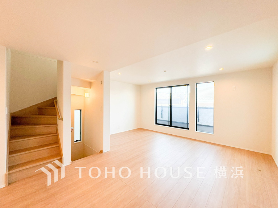 明るい光が差し込む広々としたリビング。木目調の床と白い壁が温かみのある空間を演出します。