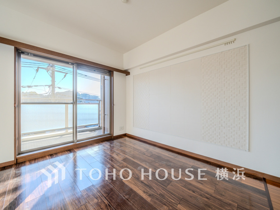 陽光が差し込む明るいリビング空間。美しいフローリングとアクセントウォールが上質な空間を演出します。