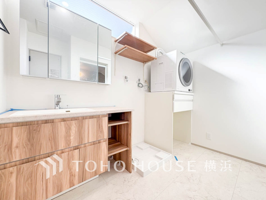 明るく清潔感のある洗面室。木目調の収納と洗濯機置き場、使いやすい棚で家事の効率を高めます。