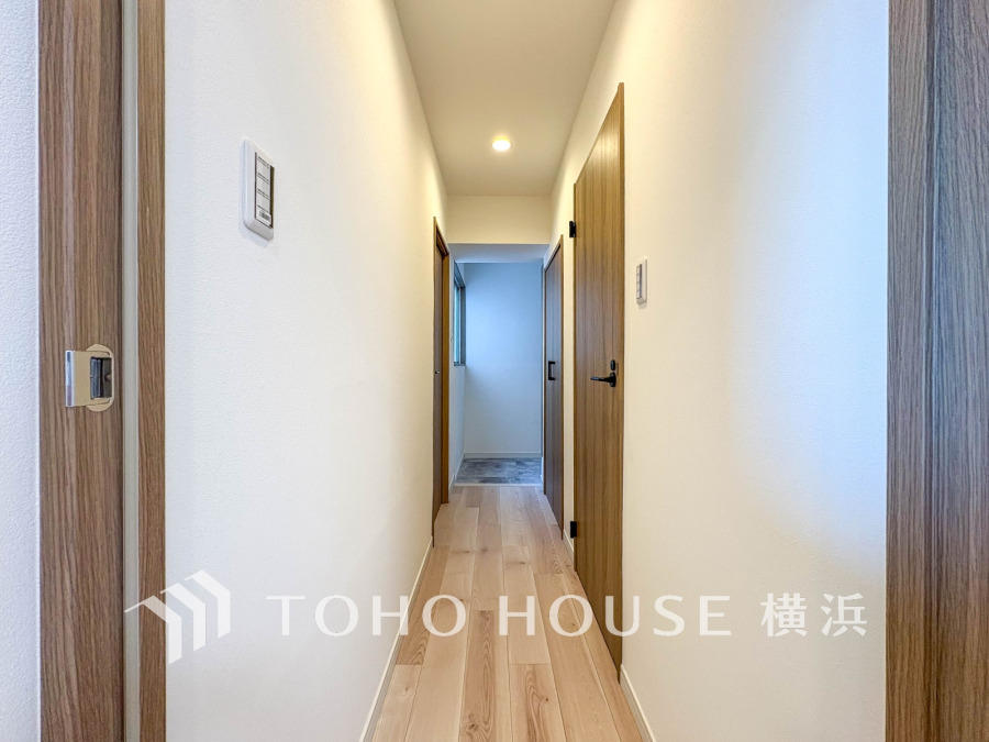 木目調の扉と明るい床材で統一された、清潔感のあるシンプルな廊下スペースです。