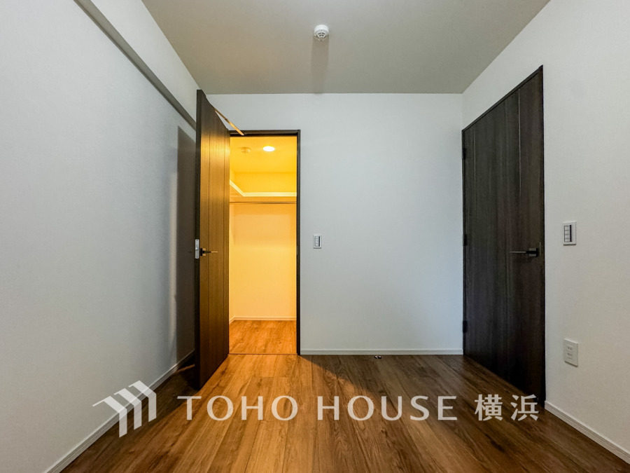 落ち着いた木目調の床と白い壁が調和したシンプルな洋室。ウォークインクローゼット付きで収納力も充実。