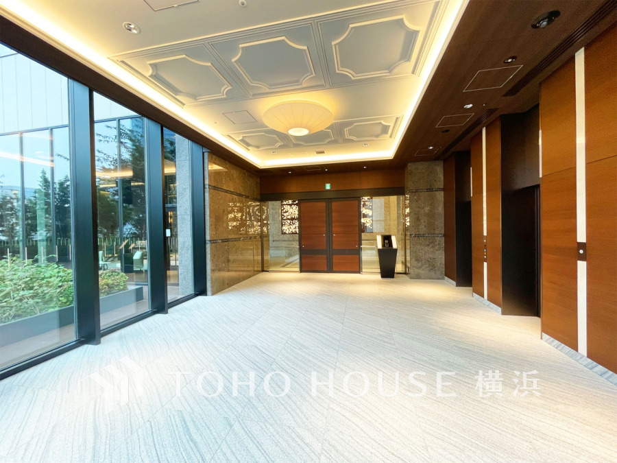 高級感ある大理石と木目調の壁面が調和した、明るく開放的なマンションエントランス。