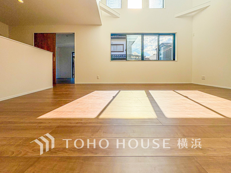 大きな窓から陽光が差し込む明るく開放的なリビング。木目調の床が温かみを演出します。