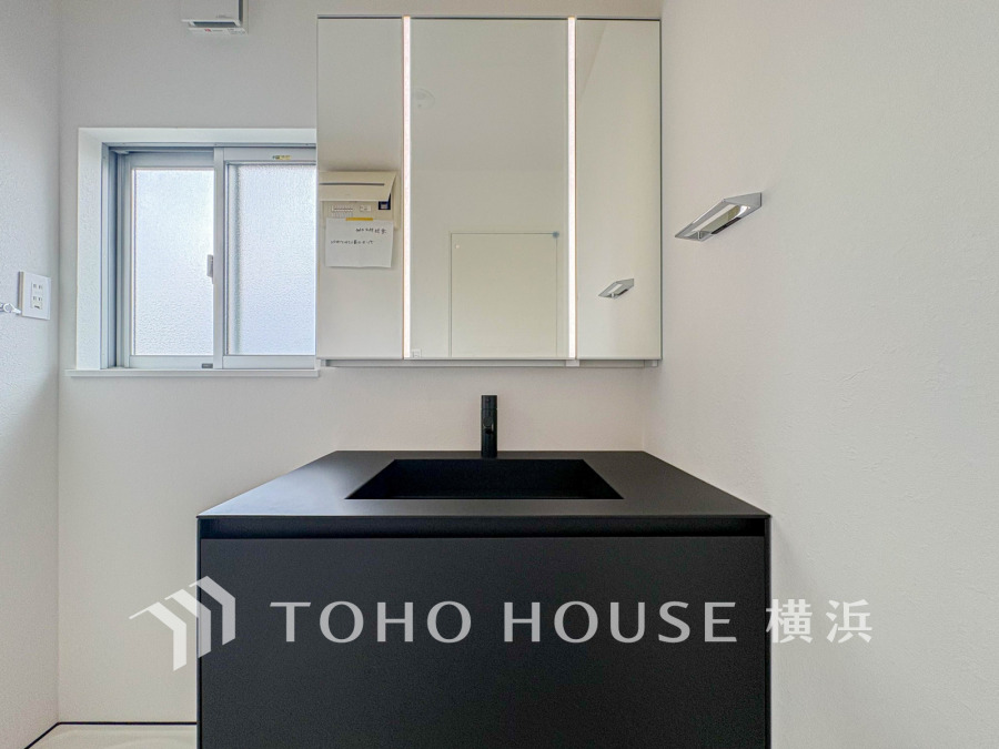 スタイリッシュなsブラックの洗面化粧台を設置した明るい洗面空間。