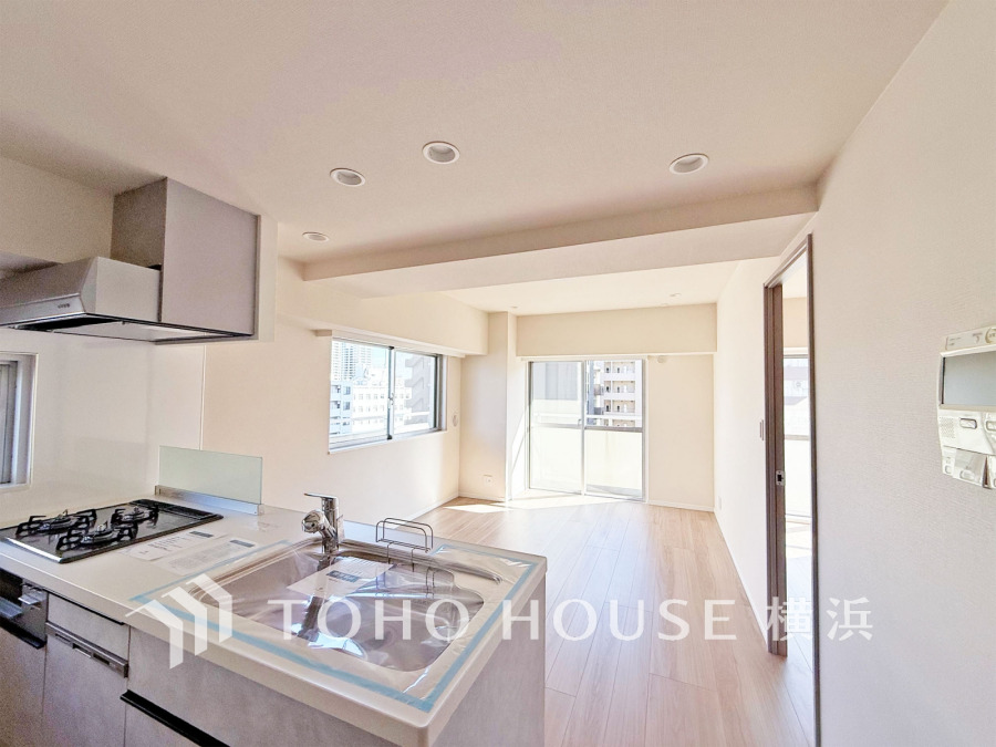 開放的な対面キッチンの明るいLDK。大きな窓から陽光が差し込み、快適な住空間を演出します。