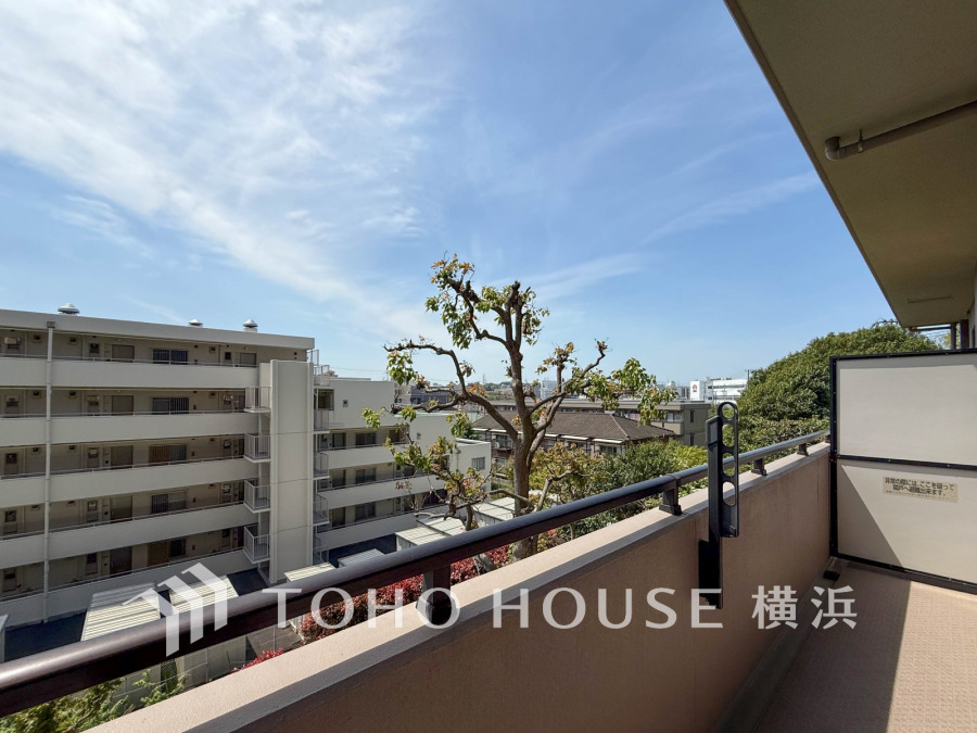 開放感あふれるバルコニーからは緑豊かな景色と青空が広がり、心地よい風を感じられます。