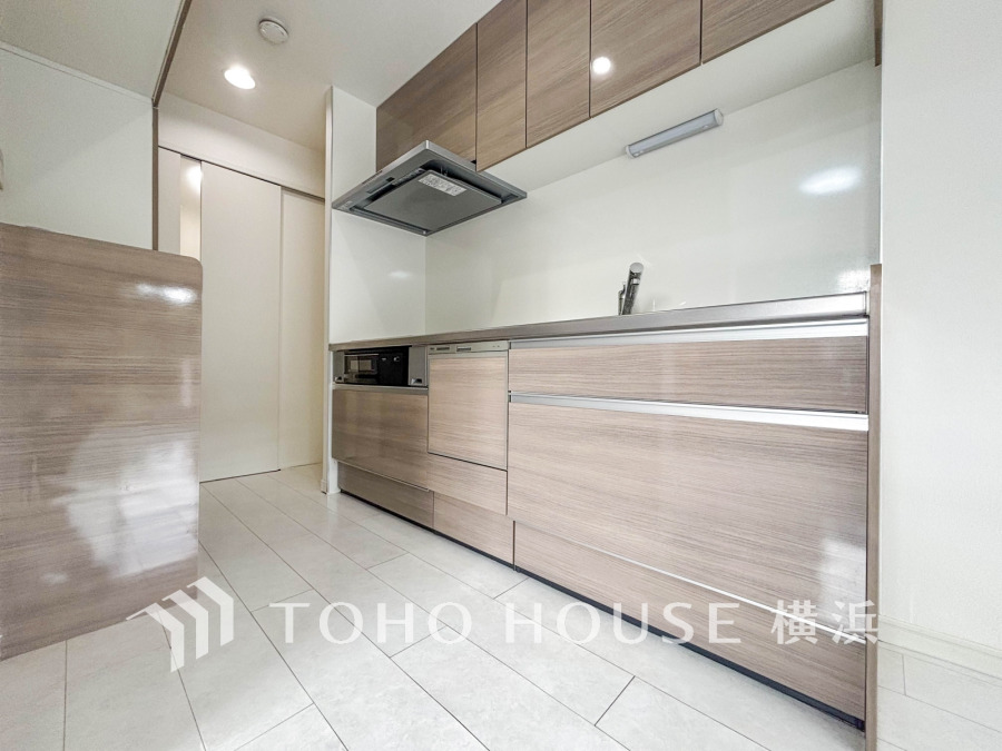 収納棚を背面に設置した統一感のあるキッチンスペースは美しく、機能性も良好です。