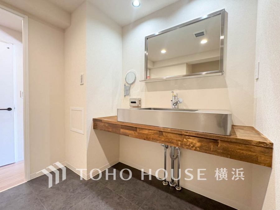 温かみのある木製カウンターと広々としたシンクが特徴の、清潔感あふれる洗面スペースです。