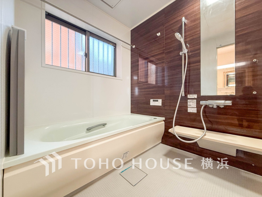 落ち着いた木目調の壁が美しい、窓付きで明るく換気もできるゆったりバスルームです。