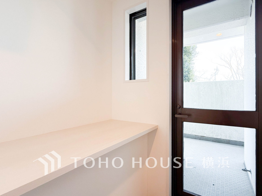 明るい窓辺に設けたカウンター付きの洗濯機置き場。バルコニーへの出入りもスムーズです。